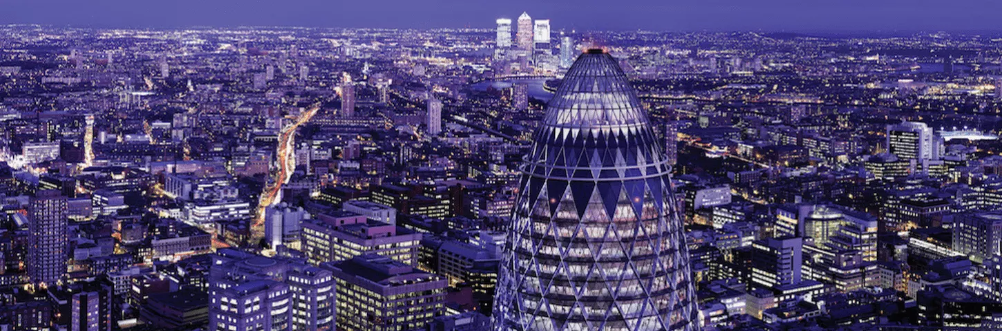 A photo of the London skyline at night with the Gherkin building in the foreground