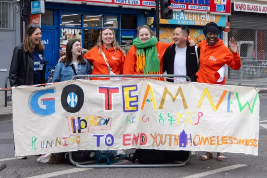 Photo of 6 people wearing orange hoodies in front of a white banner with colourful text that reads Go Team New Horizon. Running to end youth homelessness
