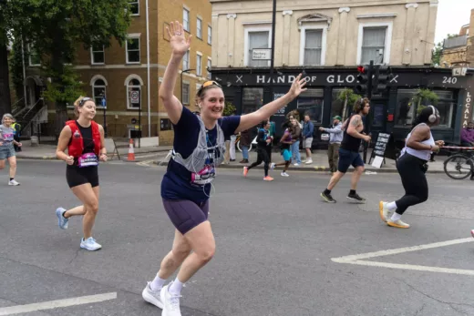 Chelsie, our Head of Youth Work, running in the Hackney Half Marathon with her arms in the air and smiling