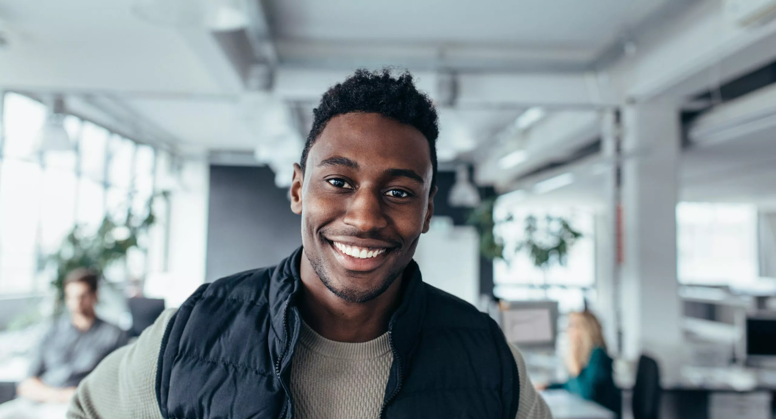 Un designer souriant, debout à son poste de travail, regarde l'objectif. Un jeune homme séduisant dans un bureau de design.