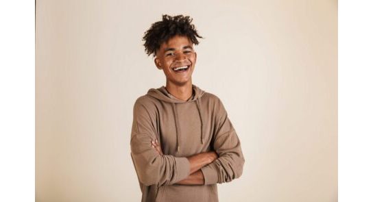 Portrait of a smiling young afro american man dressed in hoodie holding arms folded isolated