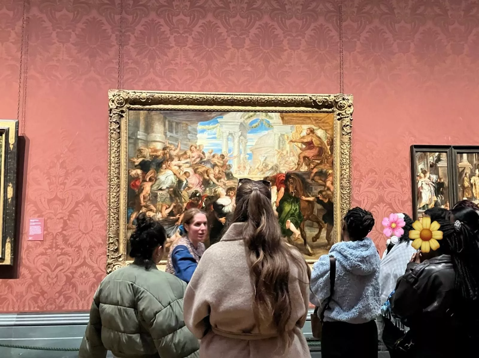 Young women standing in front of a large painting in a gallery. They have their backs to the camera as they look at the painting
